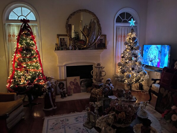 Una sala de estar con dos árboles de Navidad decorados, una chimenea y un televisor.