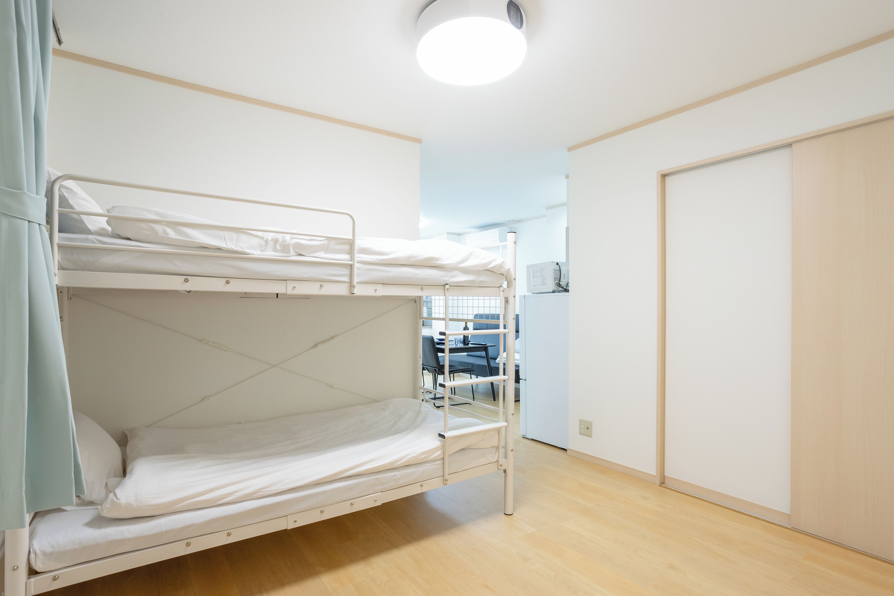 A bunk bed room with a wooden floor, a white door, and a ceiling light.