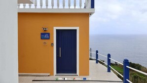Un bâtiment avec une porte bleue, une enseigne indiquant « SLAMBA », et une vue sur la mer.