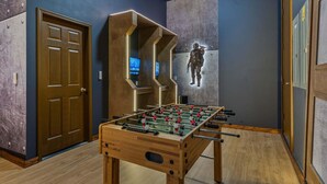 A room with a foosball table, a door, and a wall with a character mural. - Grande Golfview at Reunion-TT490 (Kissimmee)