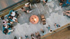 An outdoor seating area with a fire pit, wooden deck, and lounge chairs. - Noah Surf House (Torres Vedras)