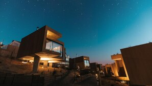 A modern, multi-level residential building with large windows and outdoor lighting. - Noah Surf House (Torres Vedras)