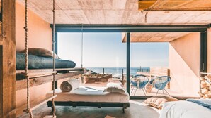 A bedroom with a bed, a hanging chair, and a view of the ocean. - Noah Surf House (Torres Vedras)