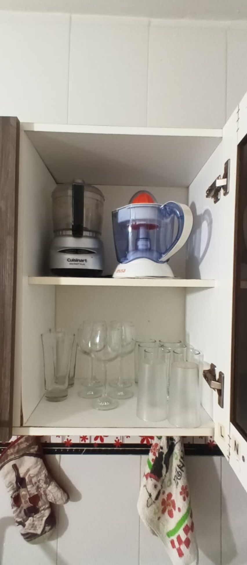Ett kök med en Cuisinart-matberedare och en mixer på den övre hyllan, och flera genomskinliga glas på den nedre hyllan.