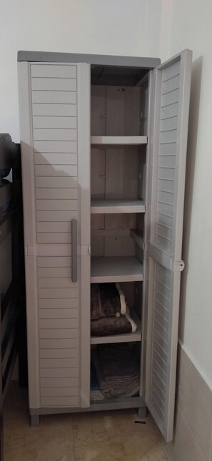 A corner wardrobe with multiple shelves and a lower hanging section. - EL CALAMAR APARTMENT (Cartagena de Indias)