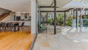 A modern interior with a dining area, kitchen, and a covered outdoor space with plants. - Macadamia Ocean Escape (Pottsville)