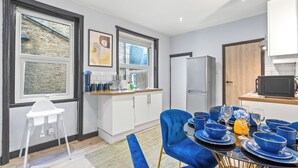 A modern kitchen with a dining area, featuring a high ceiling, large windows, and a built-in refrigerator. - Gorgeous 2BR flat in Fulham & Chelsea (London)