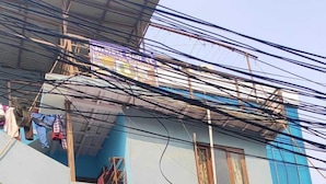 A two-story building with a sign for 'Durga Dudha Dairy' and a red sign with text in a local language. - Anand Home Stay (Kathmandu)
