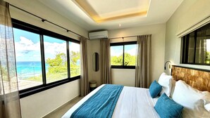 Ein Hotelzimmer mit einem großen Bett, Blick aufs Meer und einer Klimaanlage.