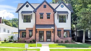 Une maison à deux étages avec une façade en briques, de grandes fenêtres et une porte d’entrée.