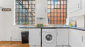 A kitchen with a washing machine, a trash bin, and a sign that reads 'ON THE ROCKS'. - 2 Bedroom Birmingham J Quarter with Parking & WiFi (Birmingham)