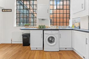 A kitchen with a washing machine, a trash bin, and a sign that reads 'ON THE ROCKS'. - 2 Bedroom Birmingham J Quarter with Parking & WiFi (Birmingham)
