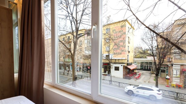Una habitación con un gran ventanal con vistas a una calle con edificios y un coche aparcado.