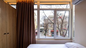Un dormitorio con un ventanal grande, una cama y un armario de madera.