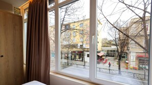 Una habitación con un ventanal grande, una cama y vistas a una calle de la ciudad.