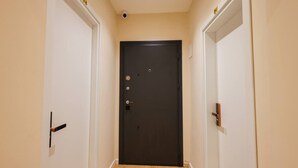 A hallway with a dark door, white walls, and a light-colored floor. - Grandstay Tirana Central 01 (Tirana)