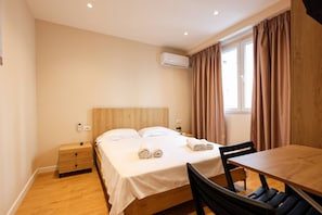 A hotel room with a bed, bedside table, chair, and a window with curtains. - Grandstay Tirana Central 01 (Tirana)