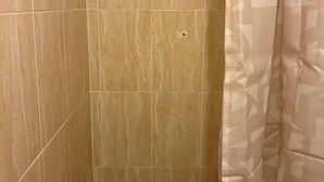 Een douchegedeelte met betegeling en een decoratief gordijn.