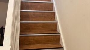 Een houten trap met witte leuningen en een witte muur.