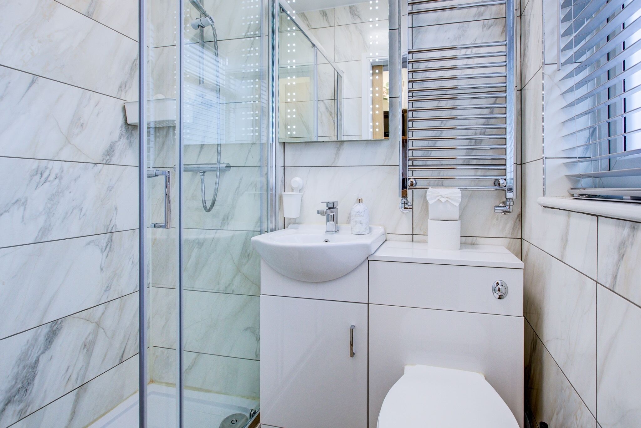 Un baño moderno con cabina de ducha de vidrio, lavabo blanco y retrete.