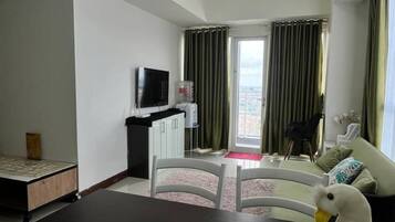 Ein modernes Wohnzimmer mit Flachbildfernseher, einem Esstisch und einer Couch.