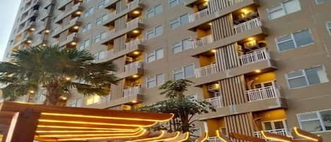 Un edificio residenziale a più piani con balconi, condizionatori e una palma in primo piano.