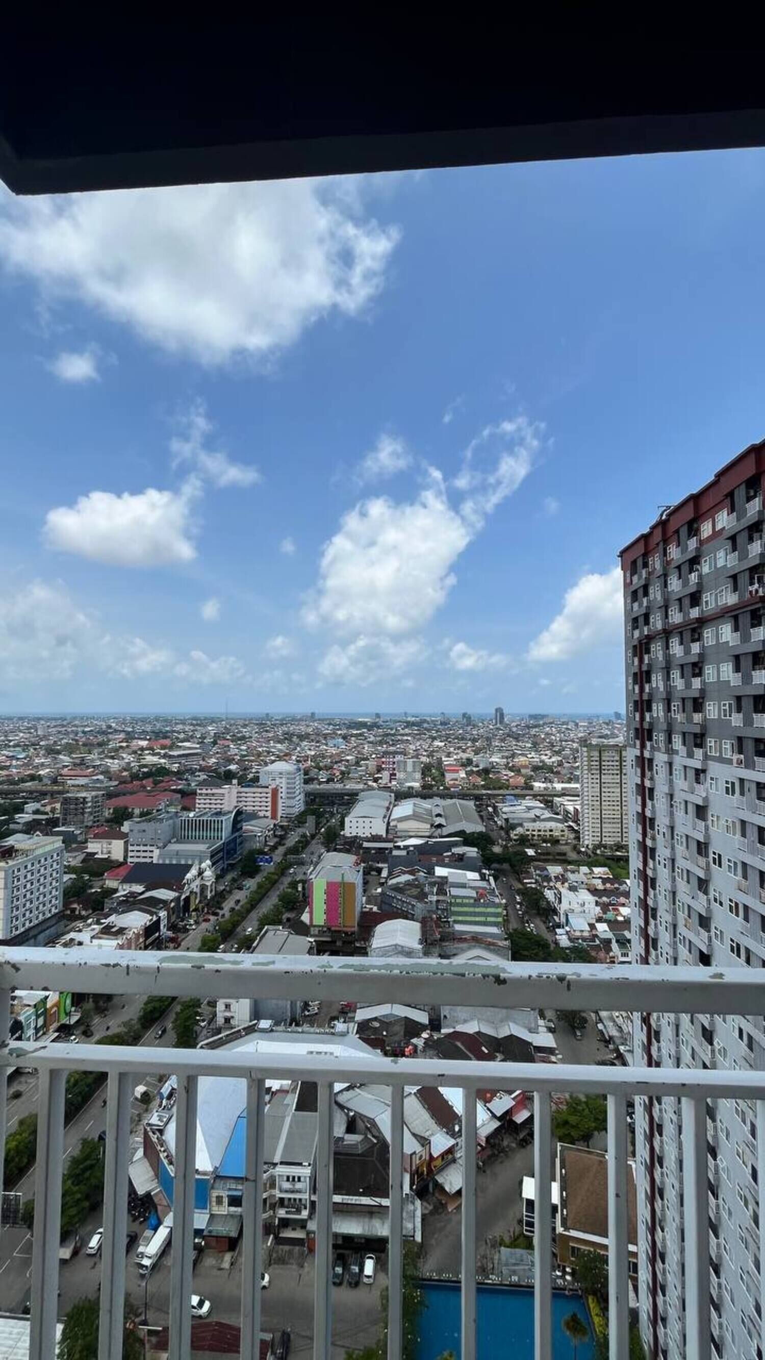 A cityscape with high-rise buildings, a clear sky, and a view of the urban area from a balcony.