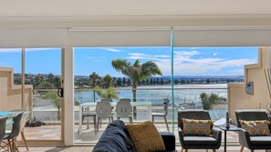 A balcony with a view of a lake, outdoor seating, and a glass door leading to the terrace. - 114 At the Bluff - 114/123 Franklin Pde, Encounter (Encounter Bay)