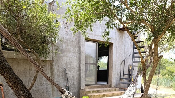 A hammock tied between trees in a grassy area with a building in the background. - COUNTRY HOUSE FOR 10 PEOPLE MERLO SAN LUIS (Córdoba)