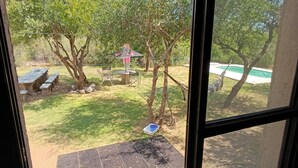 A view through a window of a backyard with a pool, a table with chairs, and a tree. - COUNTRY HOUSE FOR 10 PEOPLE MERLO SAN LUIS (Córdoba)