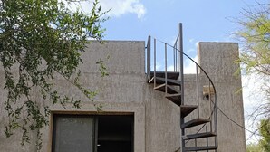 A building with a concrete exterior, a metal spiral staircase, and a door leading to an interior space. - COUNTRY HOUSE FOR 10 PEOPLE MERLO SAN LUIS (Córdoba)