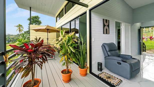 A modern outdoor seating area with a reclining chair, potted plants, and a pergola. - The Honeybee House: Spacious 2BR Jungle Home (La Fortuna)