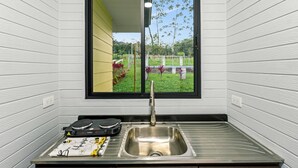A kitchen with a window, a sink, and a countertop with a coffee machine and a cutting board. - The Honeybee House: Spacious 2BR Jungle Home (La Fortuna)