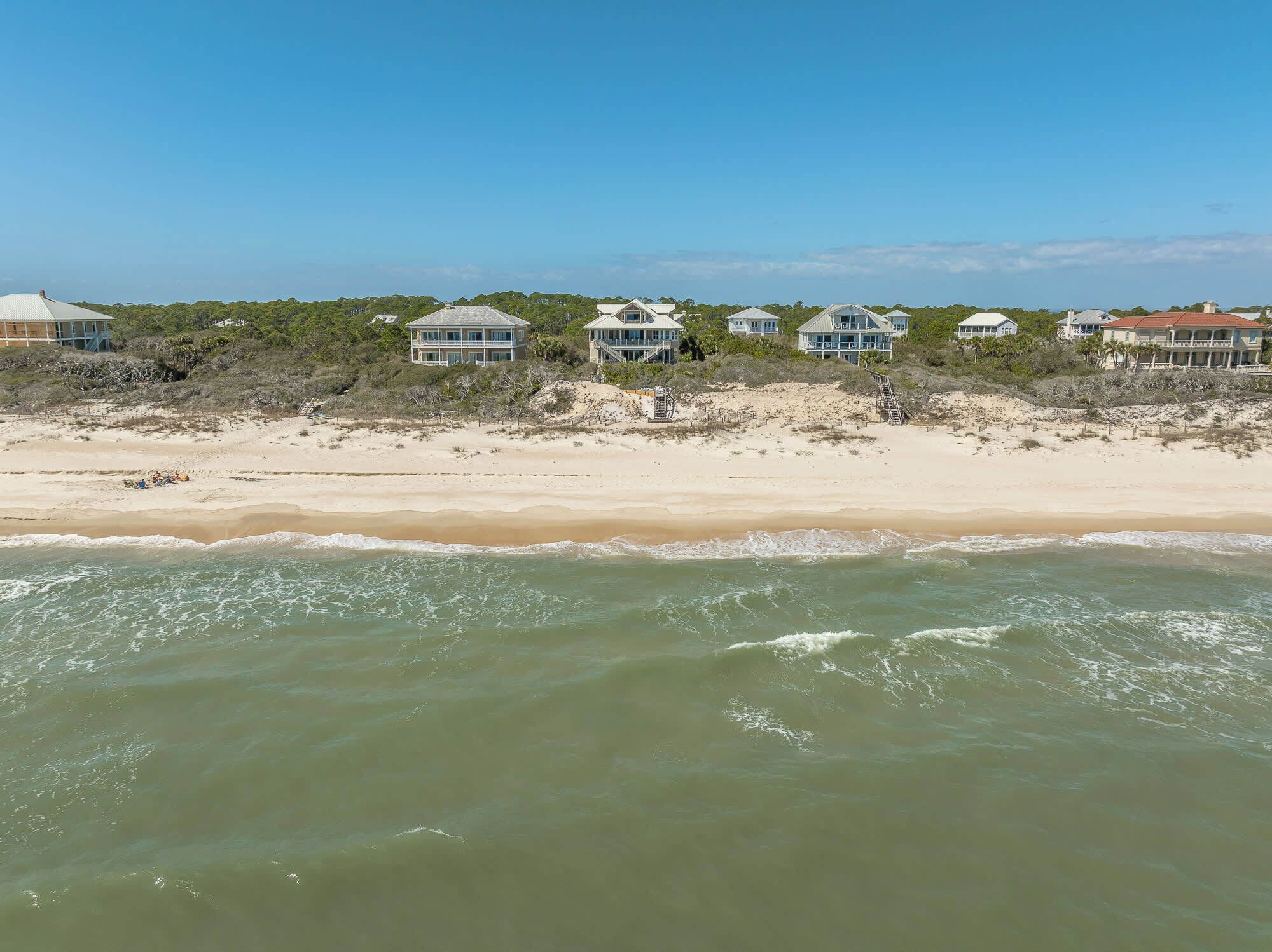 A beachfront property with multiple houses, sandy beach, and ocean view.
