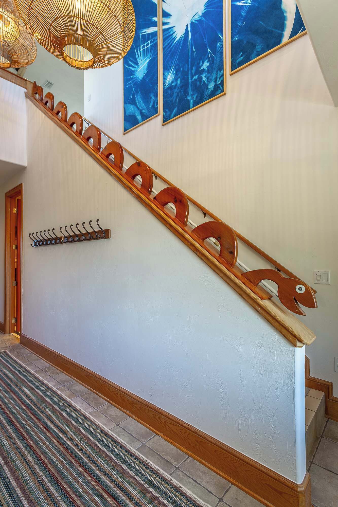 A staircase with a wooden handrail and a wall-mounted coat rack.