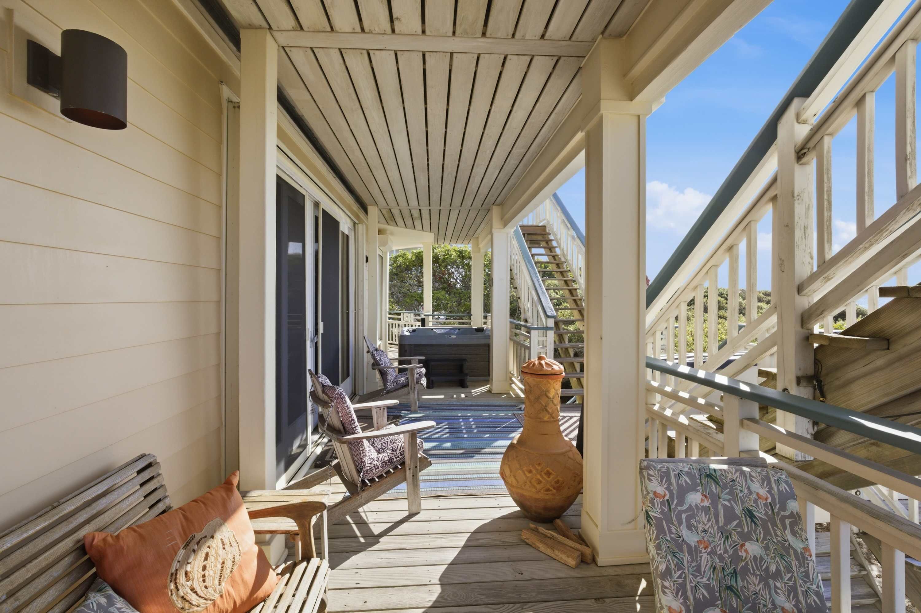 A covered porch with a wooden bench, a large vase, and a patterned chair.