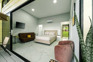 Ein Schlafzimmer mit Bett, Sofa, Fernseher und Fenster.