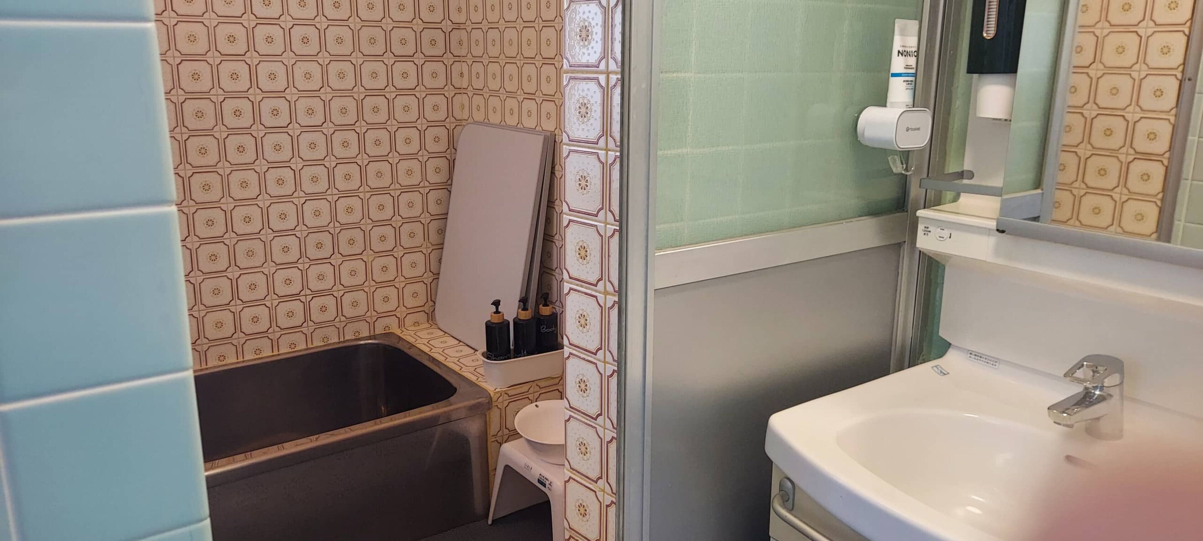 Ett badrum med handfat, spegel och hygienartiklar.