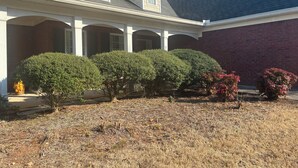 A two-story house with a covered porch, a brick wall, and several well-maintained bushes. - Cozy 2-bedroom house in serene Stockbridge with AC (Stockbridge)