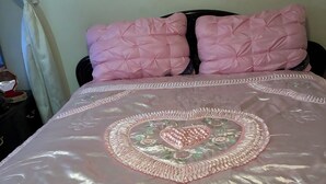 A bed with a decorative bedspread featuring a central embroidered design, two pink pillows, and a dark headboard. - Cozy 2-bedroom house in serene Stockbridge with AC (Stockbridge)