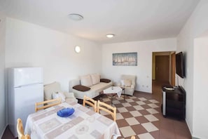 Ein kompakter Wohnraum mit Essbereich, zwei Sofas, einem Fernseher und einem Kühlschrank.