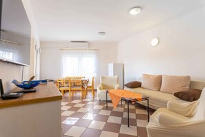 A compact living space with a dining area, a sofa, and a small table. - Holiday flat with air conditioning and balcony (Biograd na Moru)