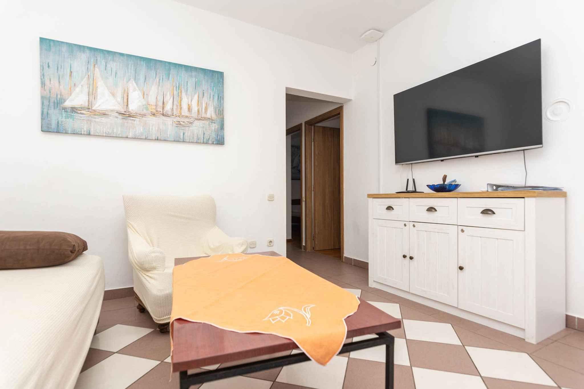 A living room with a sofa, a massage table, a cabinet, and a painting on the wall.