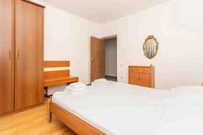 Un dormitorio con cama, armario de madera y espejo en la pared.