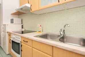 Una cocina con un lavaplatos de acero inoxidable, un microondas y una estufa.