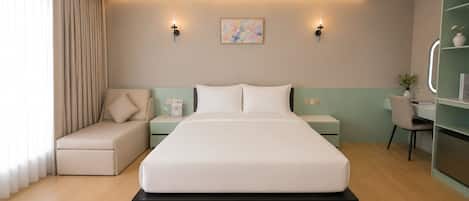 A modern hotel room with a large bed, bedside tables, a desk, and a chair.