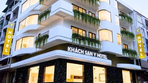 Un hotel de diversos pisos amb balcons, un cartell amb la inscripció 'KHÁCH SAN Y HOTEL' i un disseny arquitectònic modern.