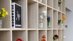 Una estanteria amb diversos ramons amb flors i un llibre titulat 'JILSANDER'.