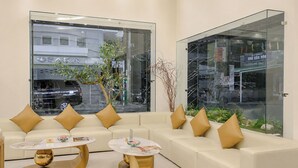 Una zona d'espera moderna amb un sofà, dues taules rodones i una partició de vidre.