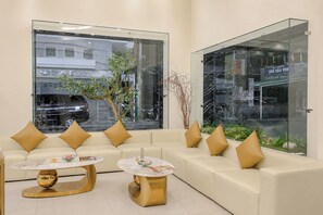 A modern waiting area with a sofa, two round tables, and a glass partition. - Y Hotel Ly Hong Thanh (Can Tho)